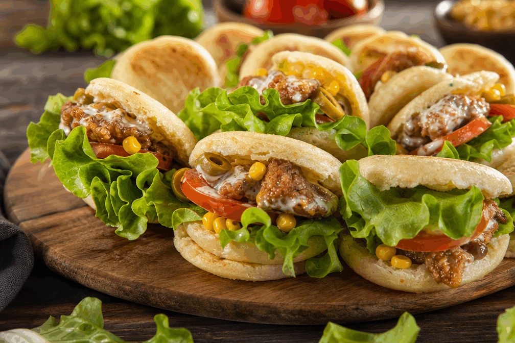 Des minis batbout farcis au poulet : 5 minutes pour une pause gourmande et réconfortante 🔥 Description Les minis batbout sont de petits pains marocains moelleux et légèrement levés, parfaits pour une pause gourmande rapide. Ici, ils sont délicieusement farcis d’une préparation savoureuse au poulet, agrémentée d’épices douces pour un équilibre parfait entre réconfort et légèreté. Ce plat convivial se déguste avec les doigts, idéal pour un encas ou un apéritif improvisé. Informations Temps de préparation : 15 minutes (pâte + farce) Temps de cuisson : 10 minutes Nombre de portions : 8 pièces Difficulté : Moyenne Ingrédients Pour la pâte au batbout 250 g de farine de blé 5 g de levure boulangère sèche 150 ml d’eau tiède 1 cuillère à café de sucre 1 pincée de sel 1 cuillère à soupe d’huile d’olive Pour la garniture au poulet 150 g de blanc de poulet 1 petite échalote 1 cuillère à soupe d’huile d’olive 1/2 cuillère à café de paprika doux 1/4 cuillère à café de cumin en poudre Sel et poivre du moulin Une poignée de coriandre fraîche hachée 50 g de fromage frais type labneh ou fromage à tartiner Préparation Prépare la pâte : dans un bol, mélange la farine, le sel, le sucre et la levure. Ajoute l’eau tiède et l’huile d’olive puis pétris jusqu’à obtenir une pâte souple et homogène (environ 5 minutes). Couvre la pâte d’un linge propre et laisse-la lever dans un endroit tiède pendant 1 heure, jusqu’à ce qu’elle double de volume. Prépare la garniture : coupe le blanc de poulet en petits morceaux. Émince finement l’échalote. Fais chauffer l’huile d’olive dans une poêle, ajoute l’échalote et fais-la revenir 2 minutes. Ajoute le poulet, les épices, le sel et le poivre puis fais cuire à feu moyen pendant 5 minutes, jusqu’à ce que le poulet soit bien doré et cuit. Laisse tiédir. Mélange le poulet avec le fromage frais et la coriandre hachée pour obtenir une garniture crémeuse et parfumée. Divise la pâte en 8 petites boules. Sur un plan fariné, étale chaque boule en cercle d’environ 8 cm de diamètre. Fais cuire les batbout à la poêle sans matière grasse, à feu moyen, 2 à 3 minutes de chaque côté jusqu’à ce qu’ils gonflent et soient dorés. Une fois les batbout refroidis, ouvre-les délicatement en deux sans les couper complètement puis farcis-les généreusement avec la préparation au poulet. Astuces Pense à ne pas trop étaler la pâte pour que les batbout gonflent bien à la cuisson. Tu peux remplacer le blanc de poulet par du poulet grillé déjà cuit pour gagner du temps. Si tu souhaites une version plus épicée, ajoute une pointe de harissa ou de paprika fumé dans la farce. Conserve les batbout dans un torchon propre pour garder leur moelleux jusqu’au moment de servir. Service Présente les minis batbout farcis sur un plat de service, accompagnés d’une salade fraîche (tomates, concombre, persil) ou d’une sauce au yaourt citronnée pour une pause gourmande à la fois simple et savoureuse. Parfaits à partager lors d’un apéritif ou d’un déjeuner sur le pouce.